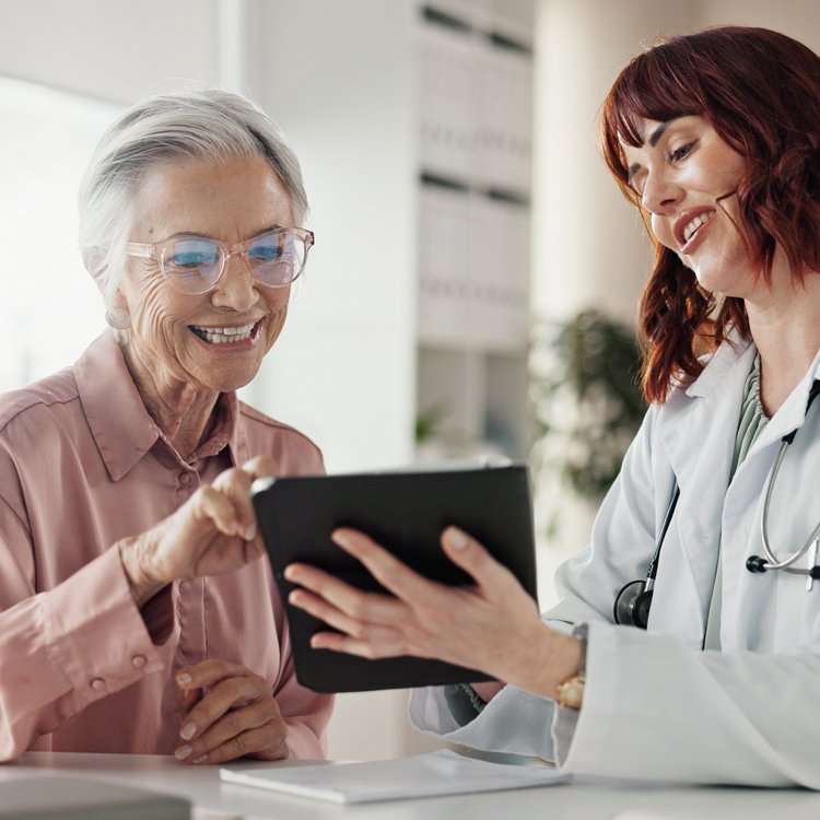 Smile, old woman and doctor with tablet for results, consultation or healthcare discussion in office. Advice, senior patient and medical professional on digital app for health, wellness and good news
